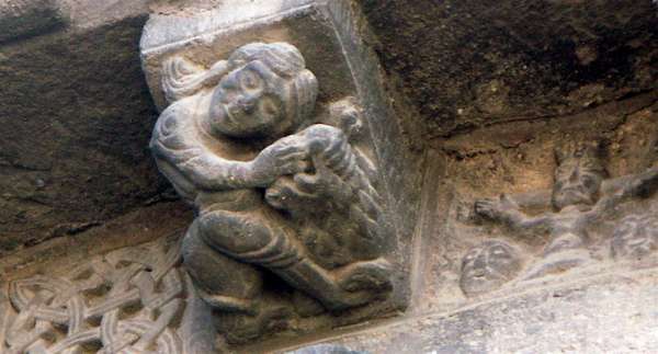 Modillon figurant un personnage et un animal, peut-être l'allégorie de la force ouvrant la gueule du lion, à l'église Saint-Julien de Brioude en Haute-Loire (France).  JPEG - 33.7 ko